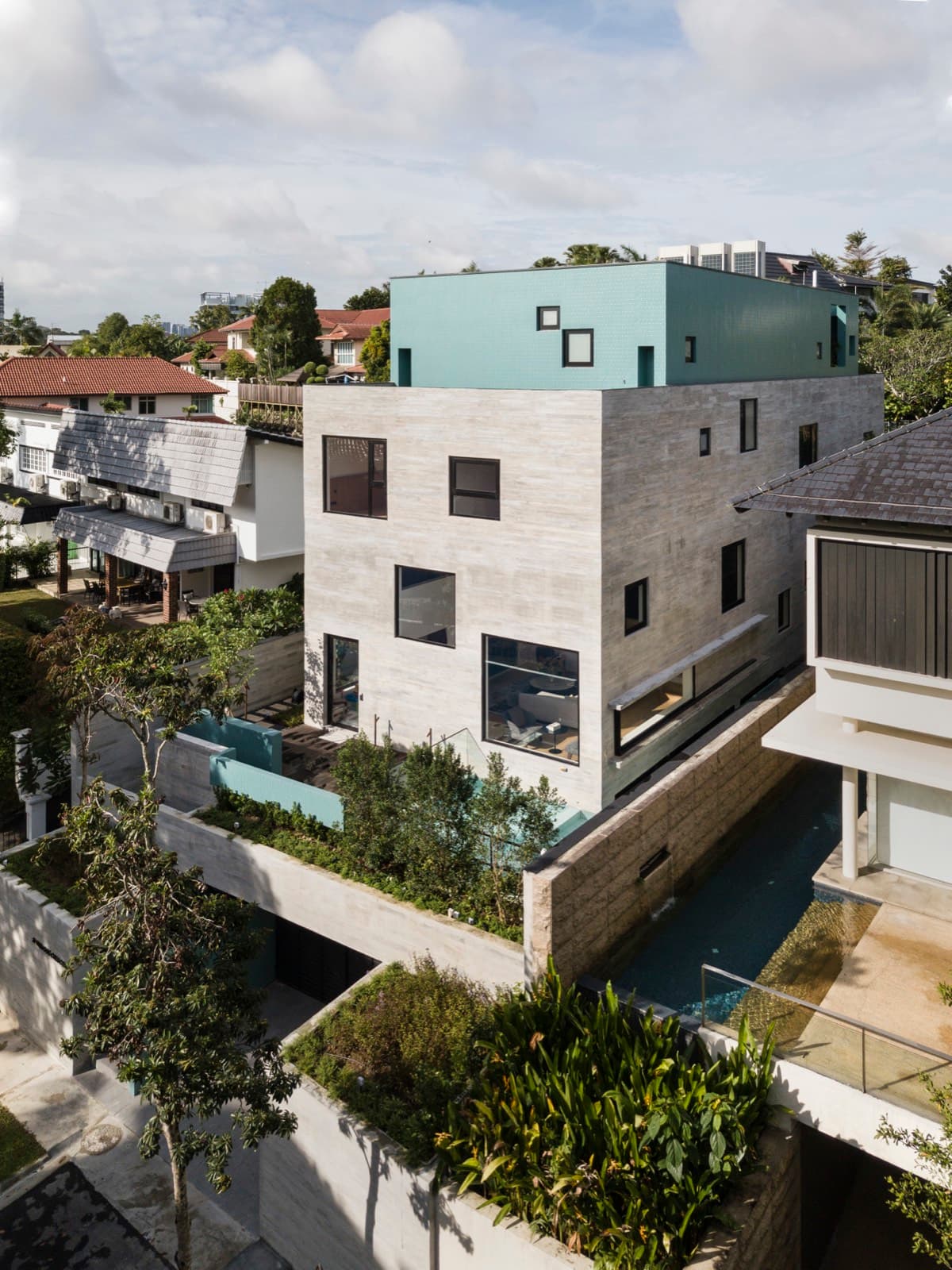 Aerial view of a boxy multi volume landed house among greenery