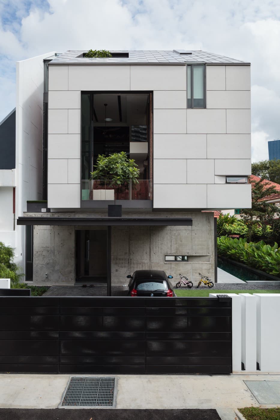 Street elevation of a completed white panelled landed house behind a dark gate
