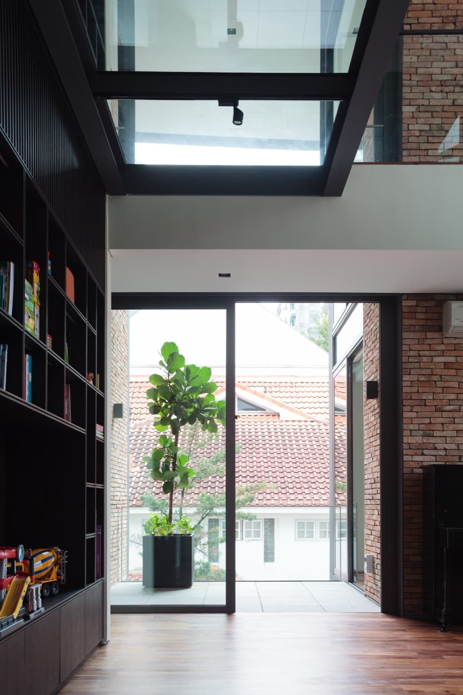 Double height hallway with brick wall and interior planting