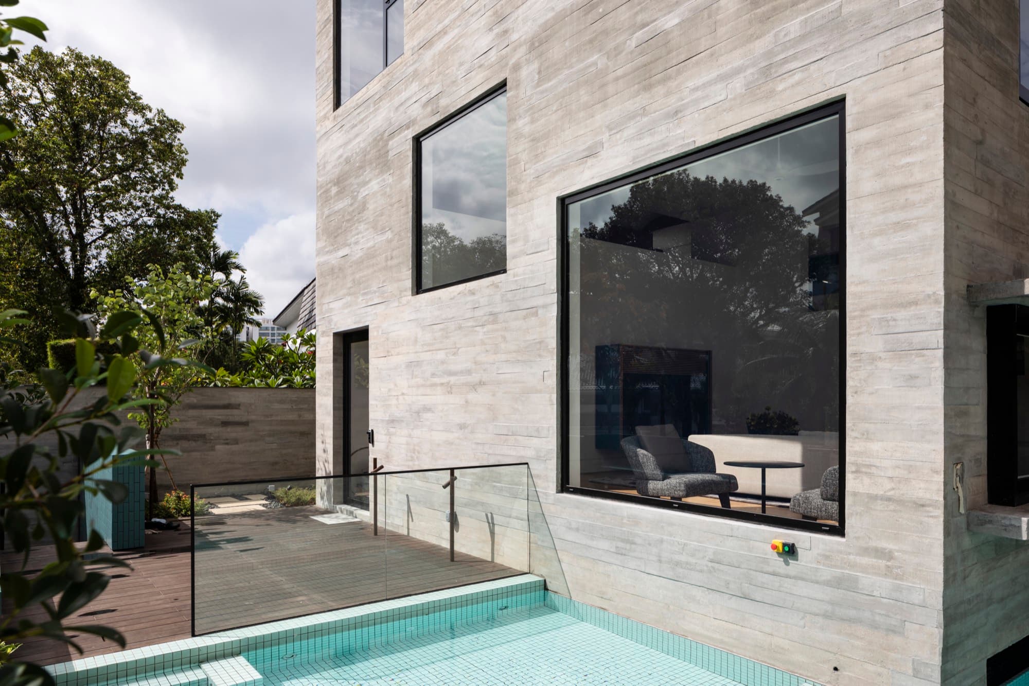 White stone clad house with cantilevered volume over a pool